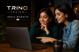 Two young Indian women reviewing the Trino Casino India website on a laptop in a modern dark editorial setting, with clean branding and no visible laptop screen.