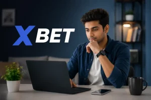 Indian Gen Z man using a laptop while researching X Bet in a modern home office